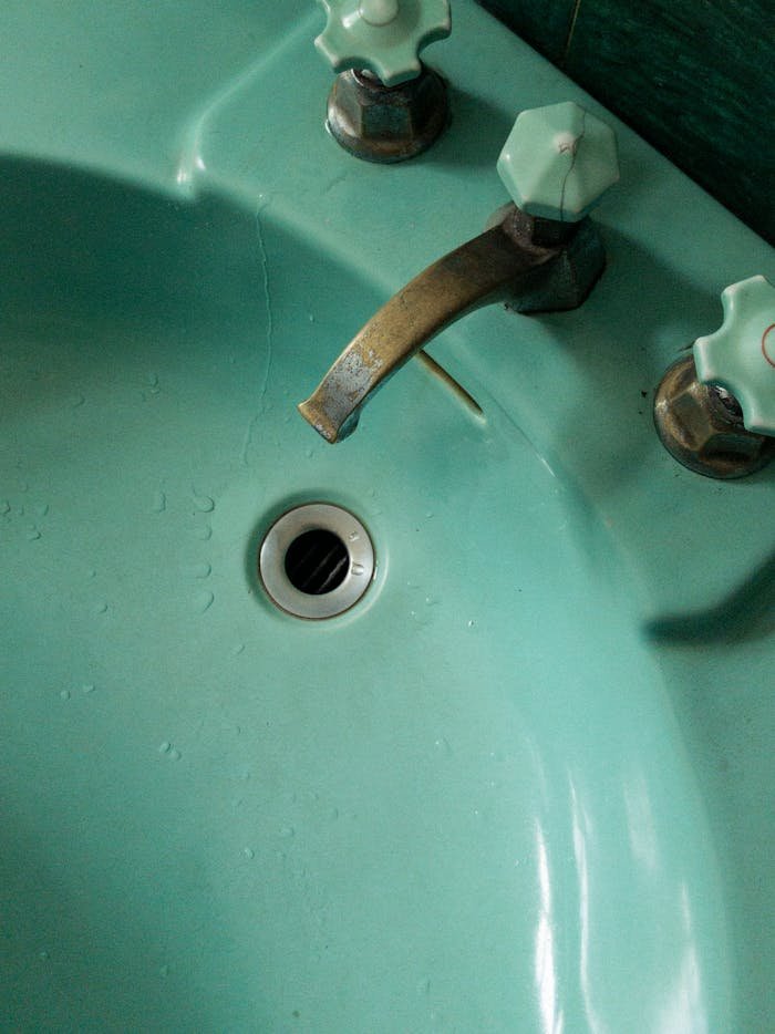 A close-up view of a vintage aqua-colored sink featuring a rusty faucet and unique decor detailing.